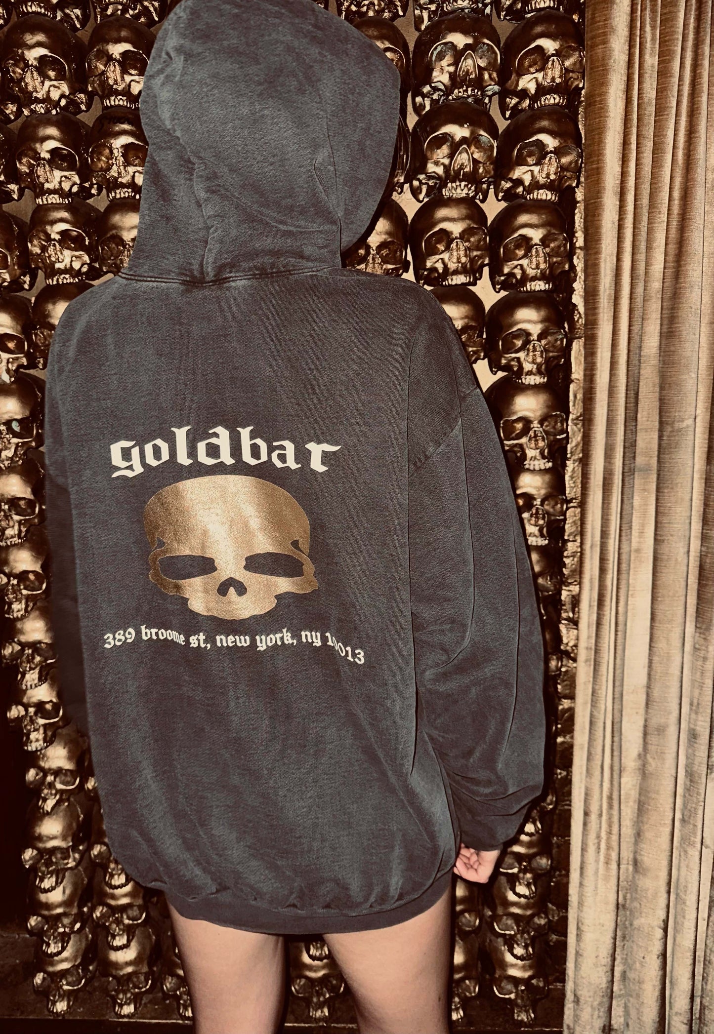 a model wearing a black Goldbar hoodie, facing away